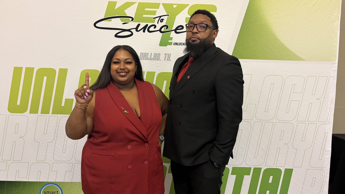 Two ALL-IN Marketing team members at the Keys to Success event in Dallas, Texas, in front of the event backdrop